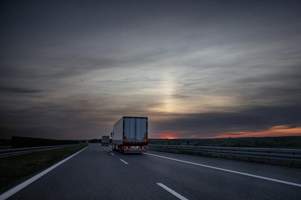 Dry van trailer heading down an empty interstate toward the sunset