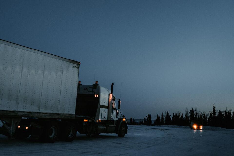 Semi truck and dry van trailer on a snowy road at dusk